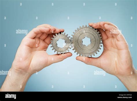 Man Holding Two Different Sizes Metallic Cog Gear Wheels In His Hands
