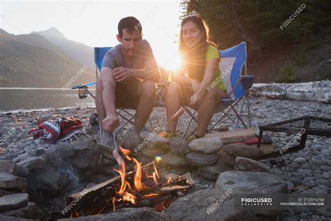 Couple Roasting Hot Dog On Campfire In Mountains — Camp Chair Together