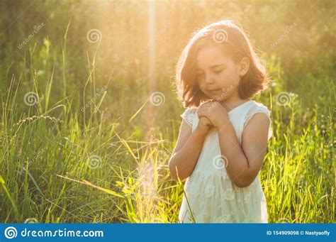Little Girl Closed Her Eyes Praying In A Field During Beautiful Sunset