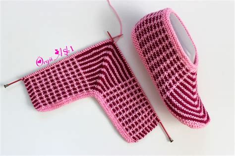 A Pair Of Pink Knitted Slippers Sitting On Top Of A White Table Next To