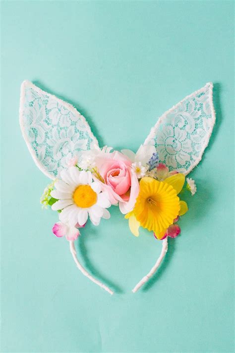 A Bunny Ears Headband With Flowers And Lace On The Top Against A Blue