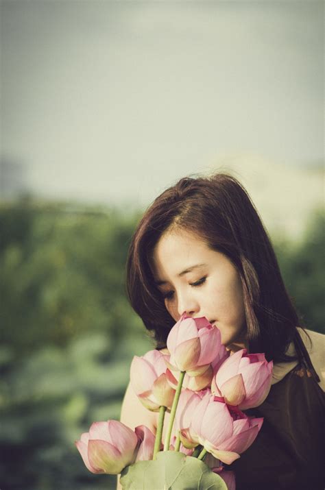 Woman In Brown And White Sniffing Pink Flowering Plant