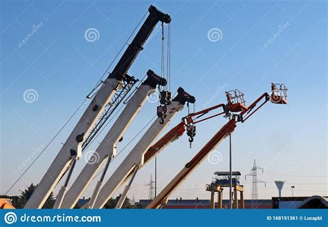 Mobile Crane Booms And Work Aerial Platforms Lined Up In An Industrial