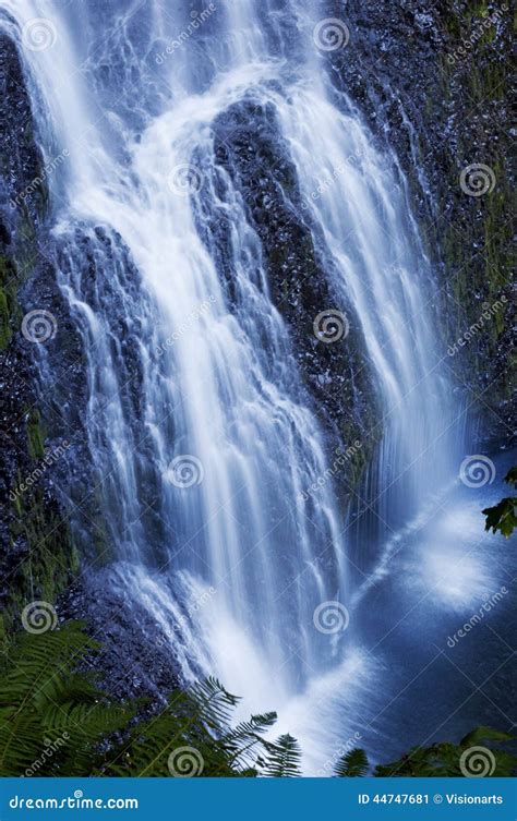 Beautiful Waterfall Cascading Over Rocks With A Soft Ethereal Blue Tone