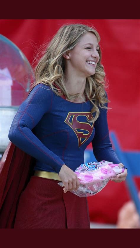 A Woman In A Superman Costume Holding A Cake
