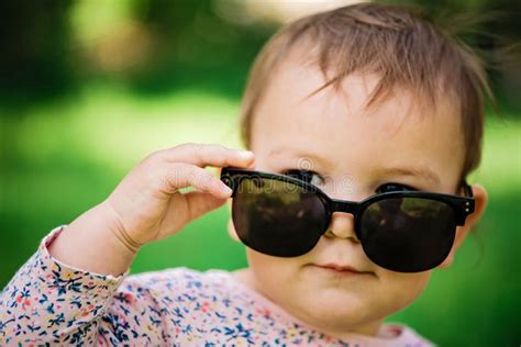 Baby With Sunglasses On The Green Grass Background On A Sunny Day