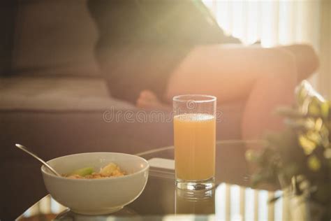 Close Up Of Breakfast On Table While Woman Sitting On Sofa Stock Image