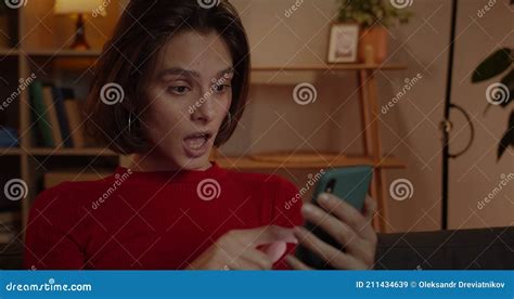 close up view of attractive female person scrolling phone screen and saying wow while sitting on