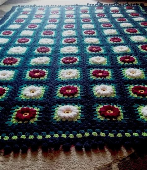 A Crocheted Blanket With Red White And Green Flowers Is On The Floor