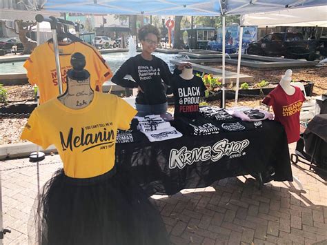 a woman standing next to a table with shirts on it