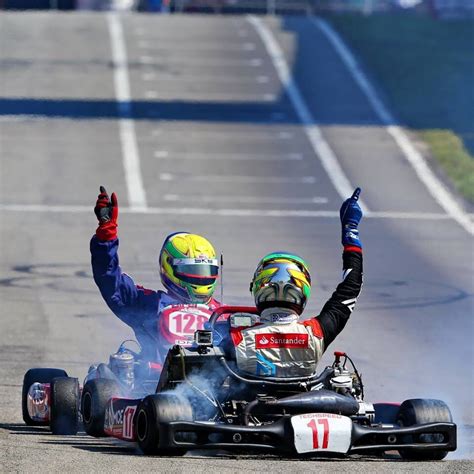 Two People On A Race Car With Their Arms In The Air And One Person