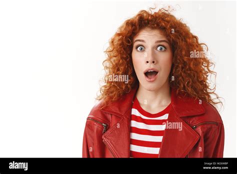 close up astonished surprised excited redhead curly haired girl blue eyes wearing stylish modern