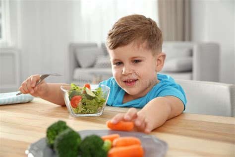 Adorable Little Boy Eating Vegetables And Salad At Table Stock Image