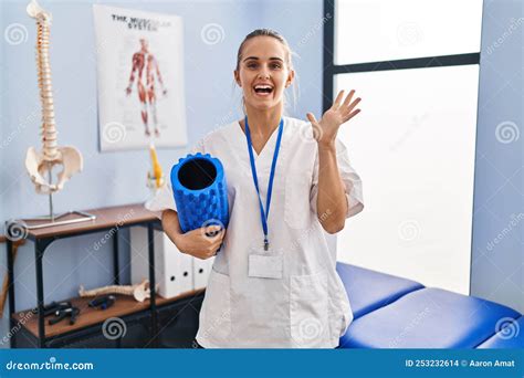 Young Physiotherapist Woman Holding Foam Roll At The Clinic Celebrating