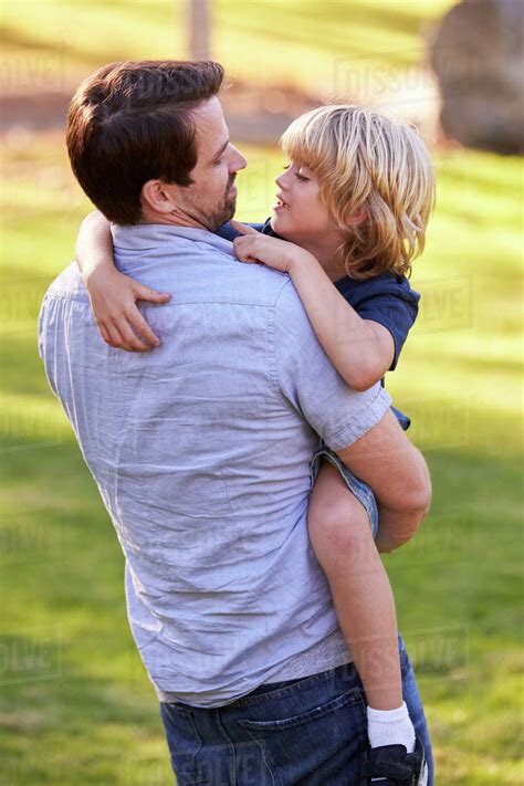 Loving Father Hugging Son In Park Stock Photo Dissolve