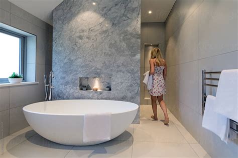 Contemporary Bathroom With White Oval Bath And Marble Background Woman Walking Into The Shower