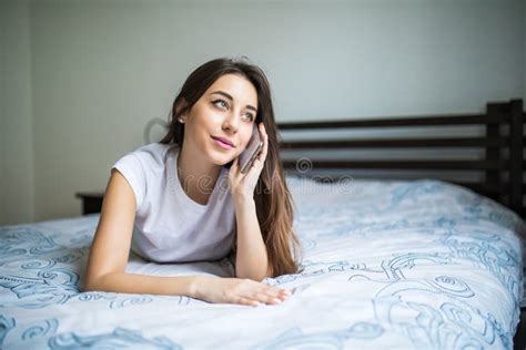 Happy Beautiful Young Woman Lying On Bed Talking On Mobile Phone And Smiling Stock Image
