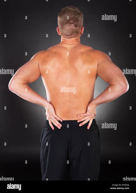 Blick von hinten auf ein nackter Oberkörper stark muskulöser Mann mit