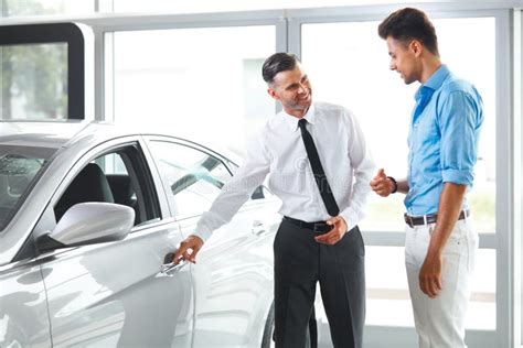 Car Sales Consultant Showing A New Car To A Potential Buyer In S Stock