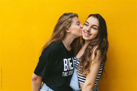 Teen Girls Kissing Over Yellow Background By Stocksy Contributor