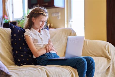 Girl Child In Headphones Resting At Home On Sofa Using Laptop Stock