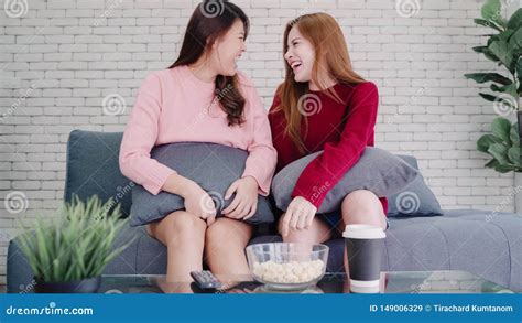 Lesbian Asian Couple Watching Tv Laugh And Eating Popcorn In Living Room At Home Sweet Couple