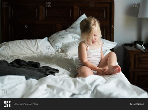 Babe Girl Sitting On Bed Contemplating Her Foot Stock Photo OFFSET