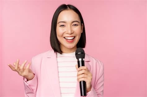 premium photo image of enthusiastic asian businesswoman giving speech talking with microphone