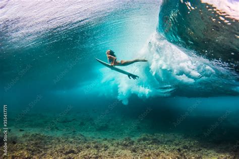 Woman In Bikini Doing Duck Dive With The Surfboard Under The Waves
