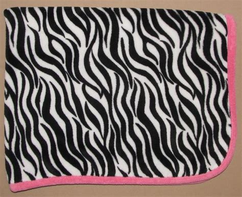 A Black And White Zebra Print Blanket With Pink Trim On The Bottom In Front Of A Tan Background