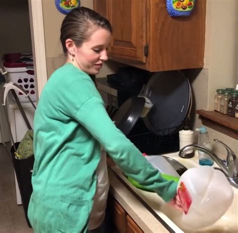 A Woman Washing Dishes In The Kitchen Sink