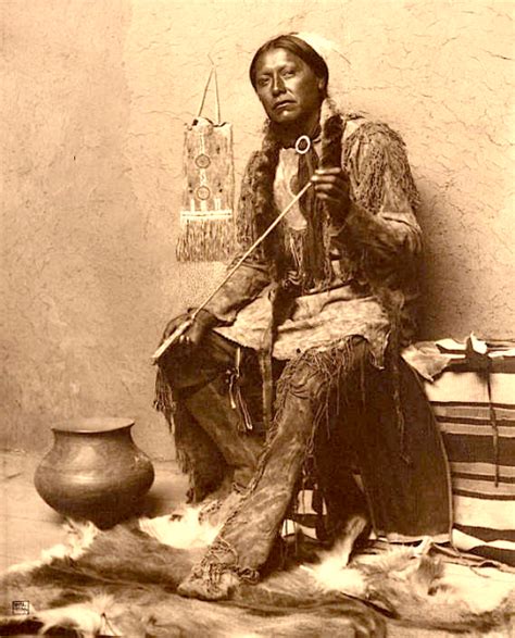 An Old Black And White Photo Of A Native American Man Sitting In Front