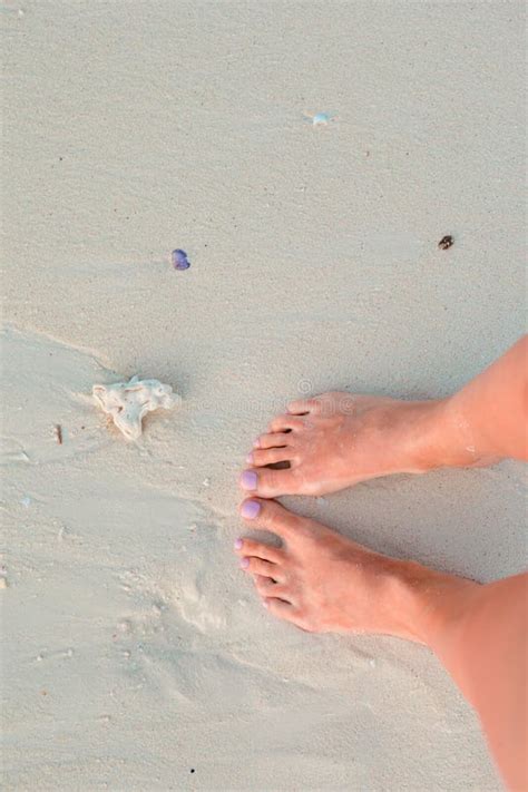 Female Tanned Slim Legs On The White Sandy Tropical Beach Stock Photo