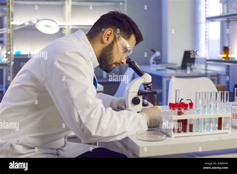 Scientist Looking In Microscope While Doing Research In Biotech Science