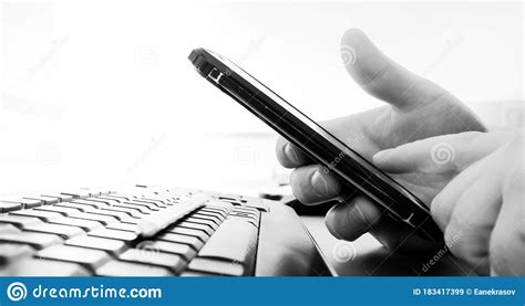 Hand Holds A Smartphone Over A Black Computer Keyboard Stock Image