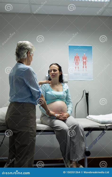 Female Doctor Talking With Pregnant Woman In Examination Room Stock