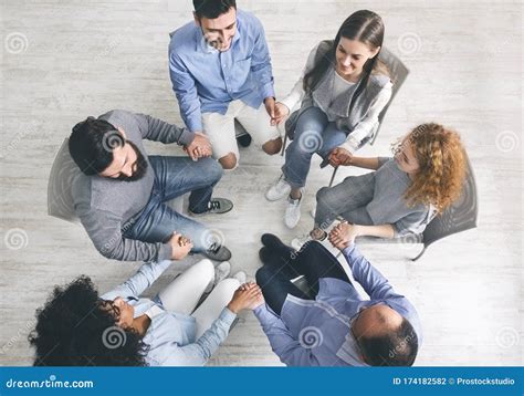 Group Therapy Patients Sitting In Circle And Holding Hands During