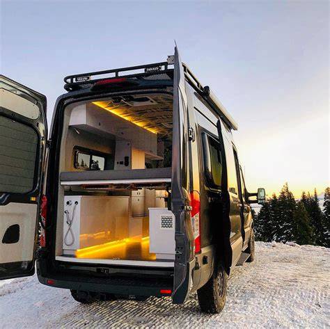 Interior of a Ford Transit van converted into a cozy camper with sleeping area and storage